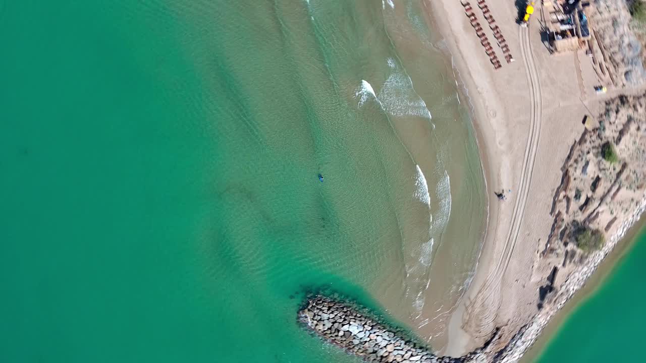 一个孤独的滑板冲浪者在西班牙巴塞罗那的ginesta港附近，海浪和防波堤，鸟瞰图视频素材