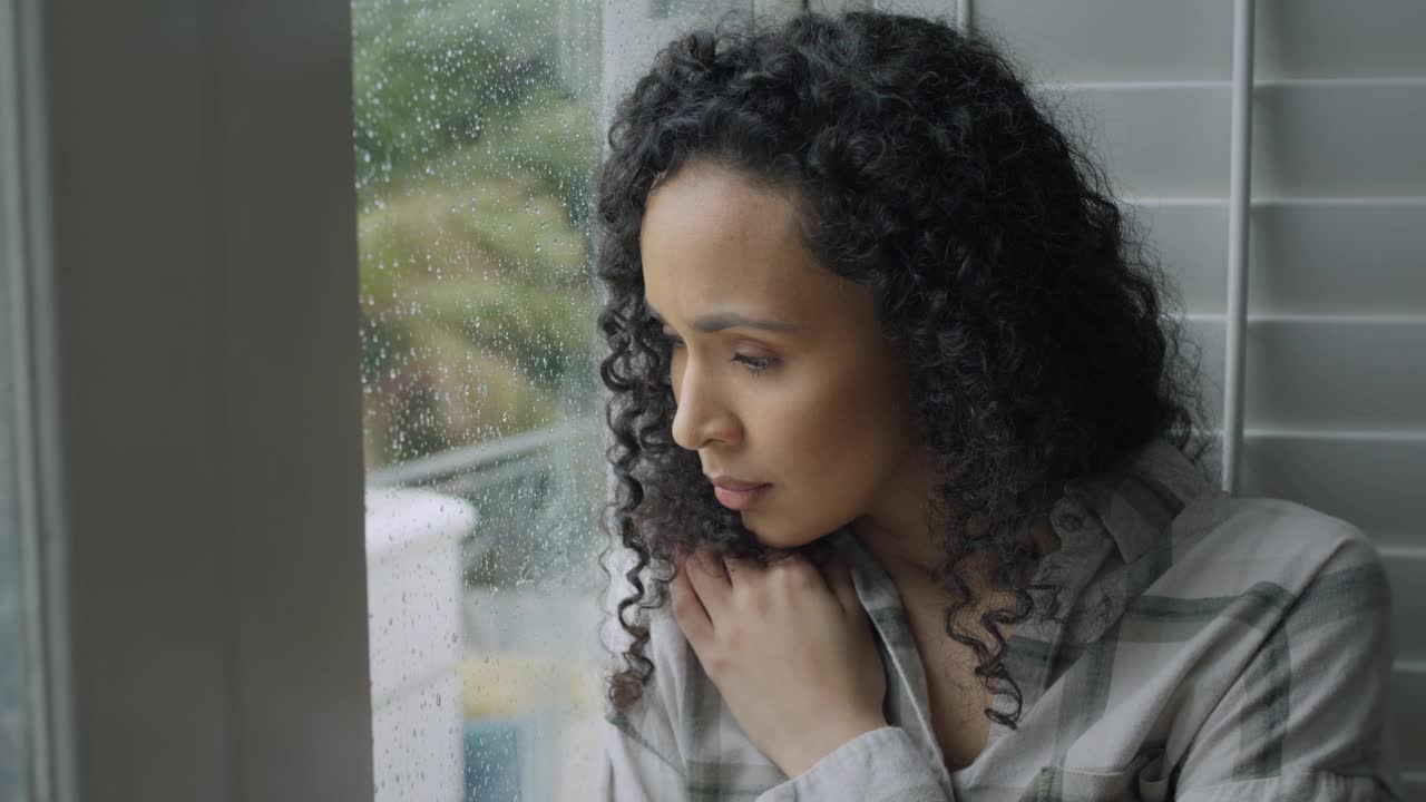 悲伤，女人和思考在下雨天压力与焦虑或抑郁在家的窗口。失意的年轻女性在心理健康方面望着窗外，在室内疲劳或失误视频素材