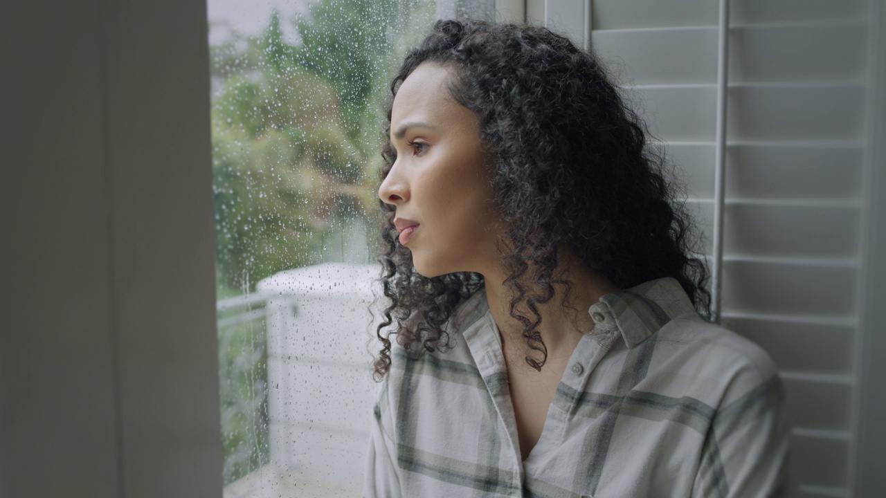 女人，思考和窗口抑郁的早晨下雨，焦虑或压力在家里。悲伤的年轻女性望着窗外的玻璃或雨，精神健康，疲劳或错误，在房子里疑惑视频素材