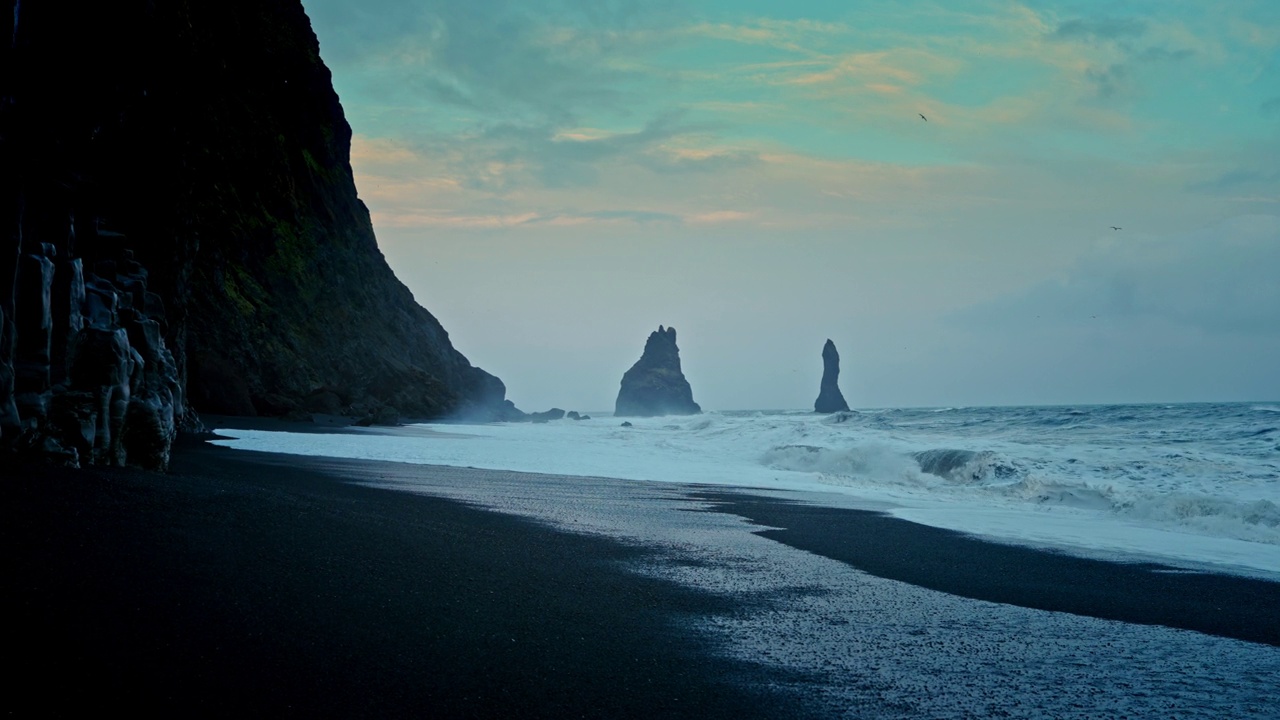 冰岛维克附近的Reynisfjara海滩全景。黑沙滩。北大西洋上引人注目的火山地标。崎岖的海岸线。海浪拍打着海岸。黑色的岩石峭壁。视频素材