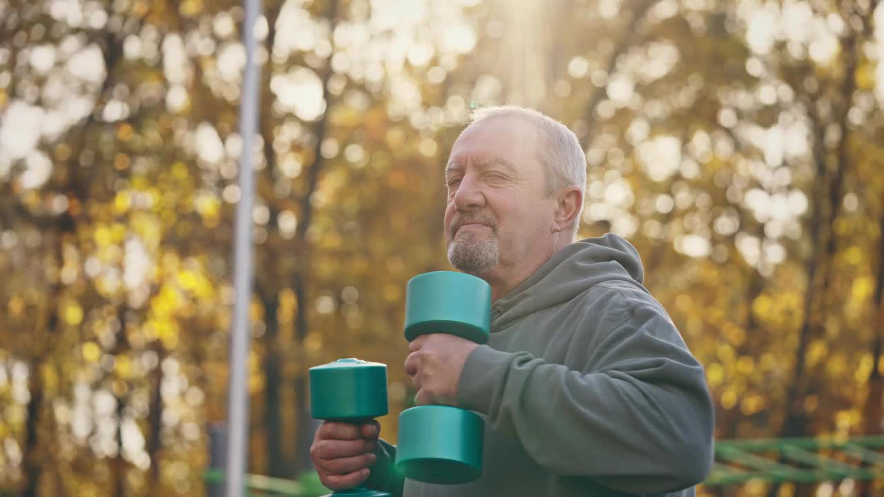 一位老人在户外用哑铃锻炼。健康的生活方式，健身视频素材