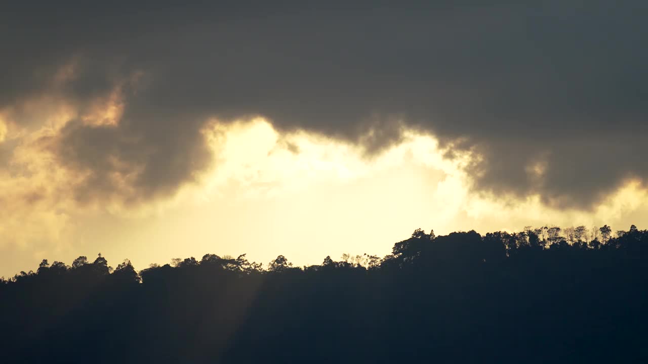 黄色的夕阳照在树木环绕的山上。视频素材