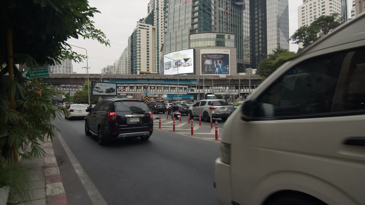 汽车行驶在被高楼大厦包围的繁忙的城市街道上视频素材