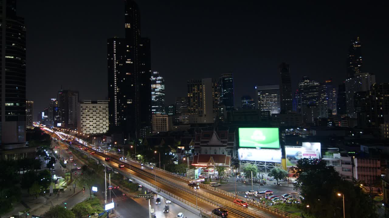 车辆沿着城市街道动态移动，周围是灯火通明的高层建筑和夜晚的天际线视频素材