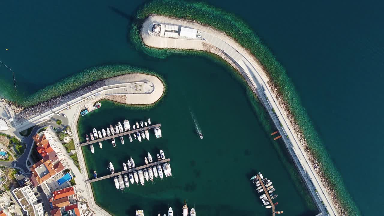 卢斯蒂卡湾鸟瞰图，亚得里亚海，黑山。建筑物的俯视图，海港码头，停泊的船只和游艇以及以山脉为背景的灯塔。新型现代豪华度假胜地视频素材