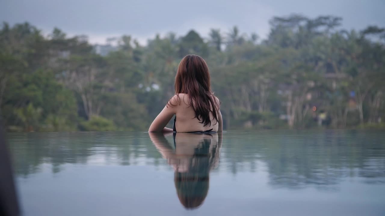 女人在无边泳池里欣赏雨林美景视频素材