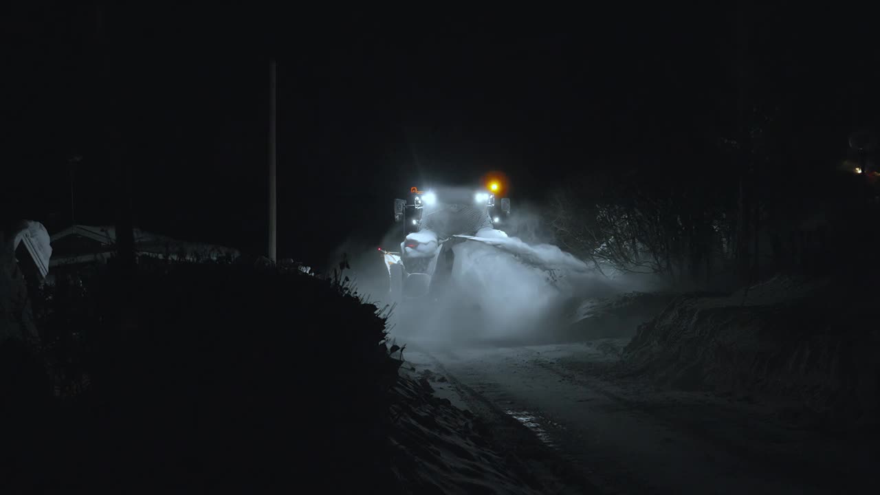 大拖拉机上的轮子从路边吹雪。清扫街道，雪后除雪。冬季市政服务。夜间后方视频视频下载