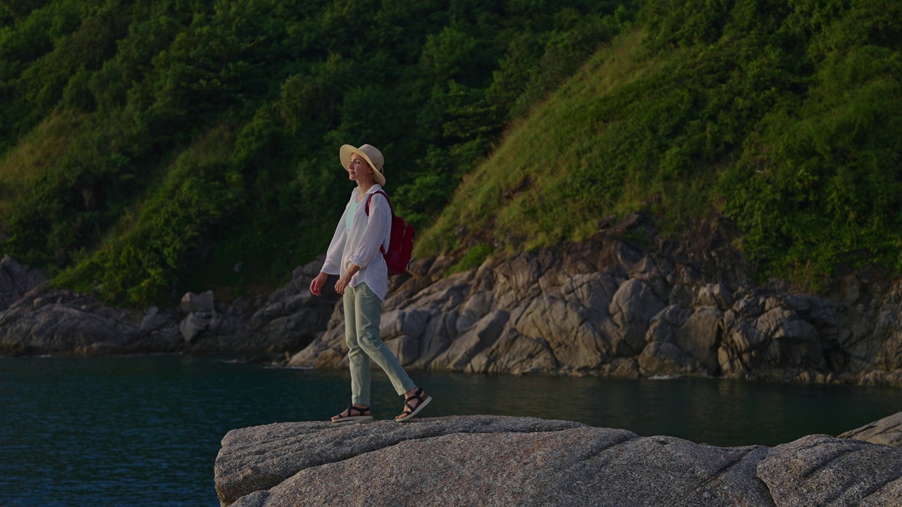 女子站在山间湖畔，被自然景观和水所环绕视频素材