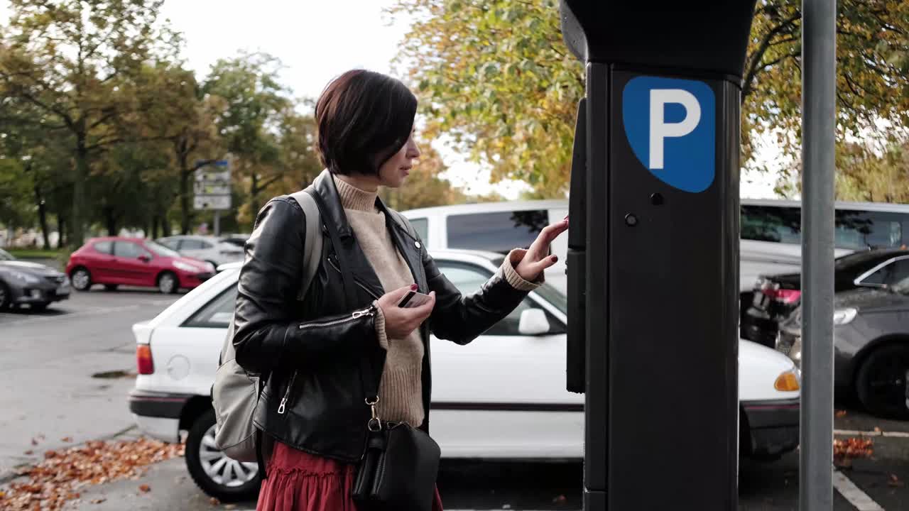 妇女通过停车计时器支付停车费用视频素材