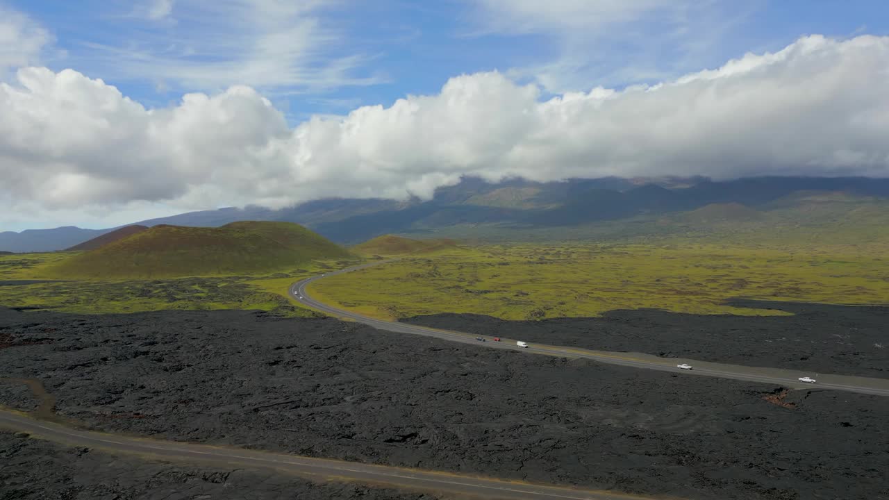 无人机拍摄的车辆行驶在道路上通过夏威夷莫纳克亚火山的土地视频素材