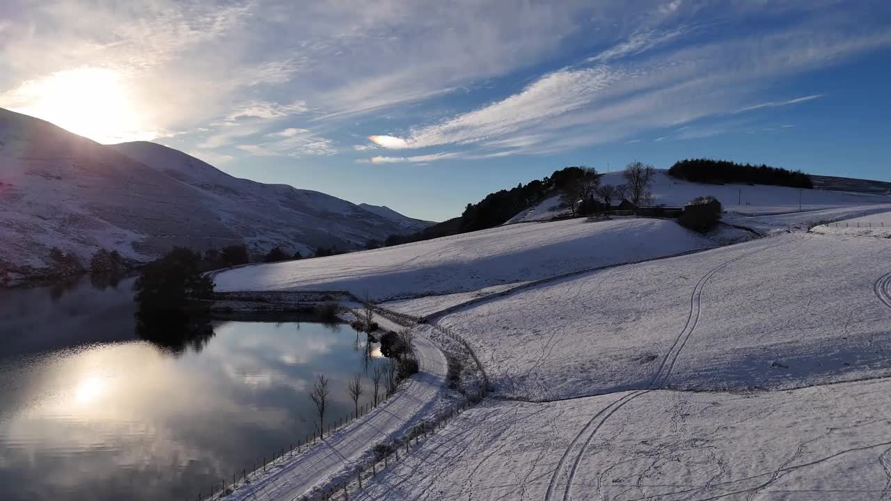 无人机拍摄的苏格兰雪山上的冬日日出，倒影在湖面上视频素材