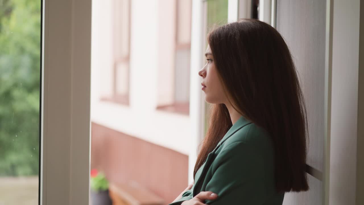 女人的目光停留在外面持续的降雨上视频素材