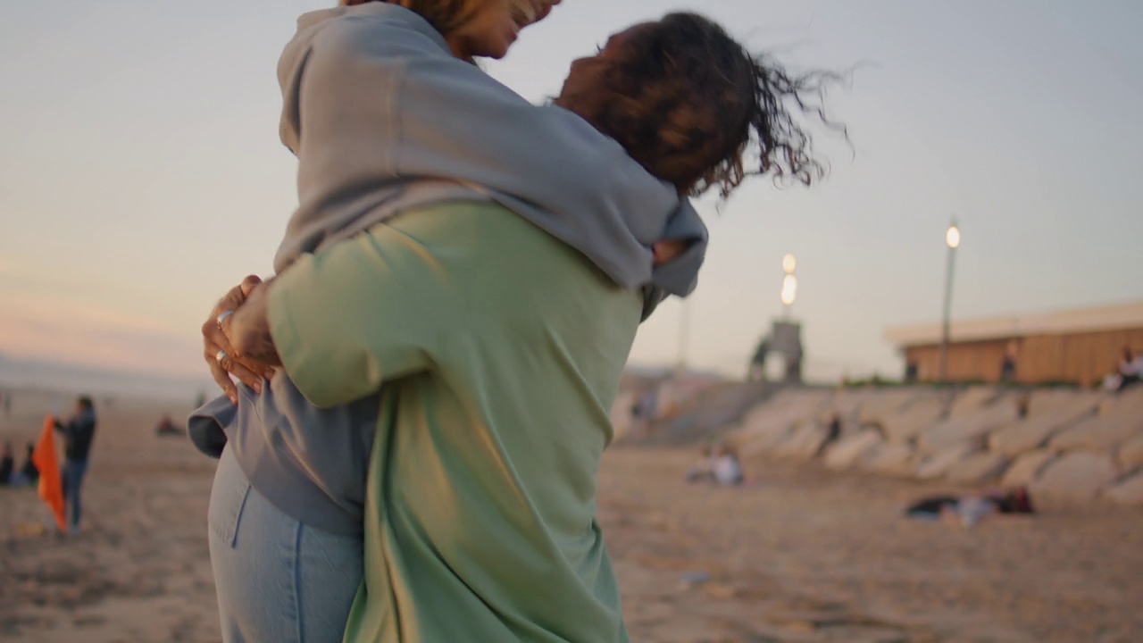 兴奋的情侣拥抱在海洋日落海滩特写。男人甩女友视频素材