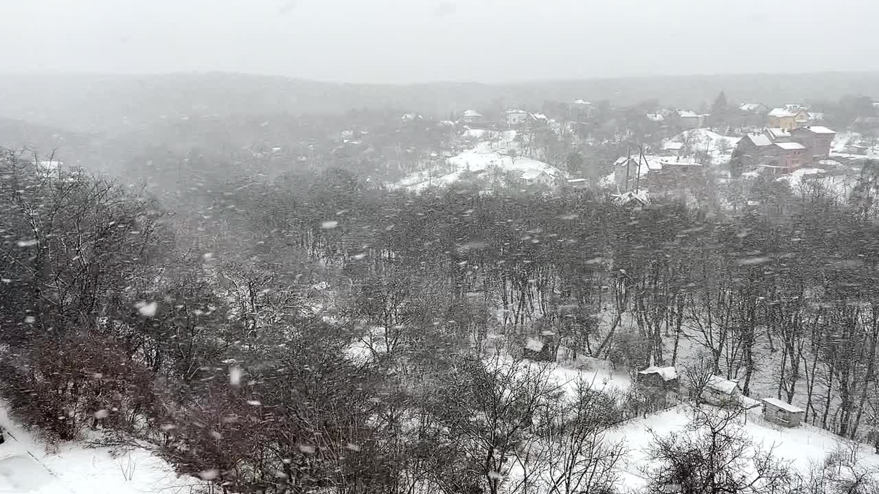 大雪的背景是森林里的树木和农舍。视频素材