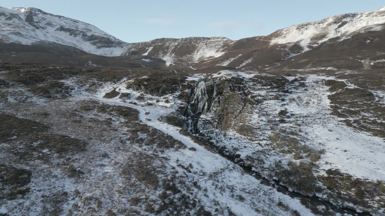 新娘的面纱瀑布在岛上的天空，小雪覆盖崎岖的地形，冬季，鸟瞰视频素材