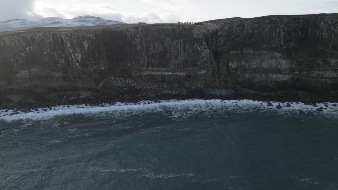 苏格兰基尔特岩(Kilt Rock)悬崖边的景色，远处是白雪皑皑的山脉，海浪拍打着海岸视频素材