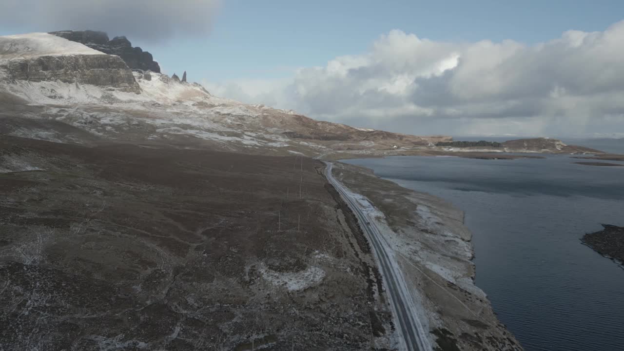 苏格兰天空大桥附近的雪山景观，可以清晰地看到蜿蜒的道路和周围的水域，这是白天拍摄的鸟瞰图视频素材