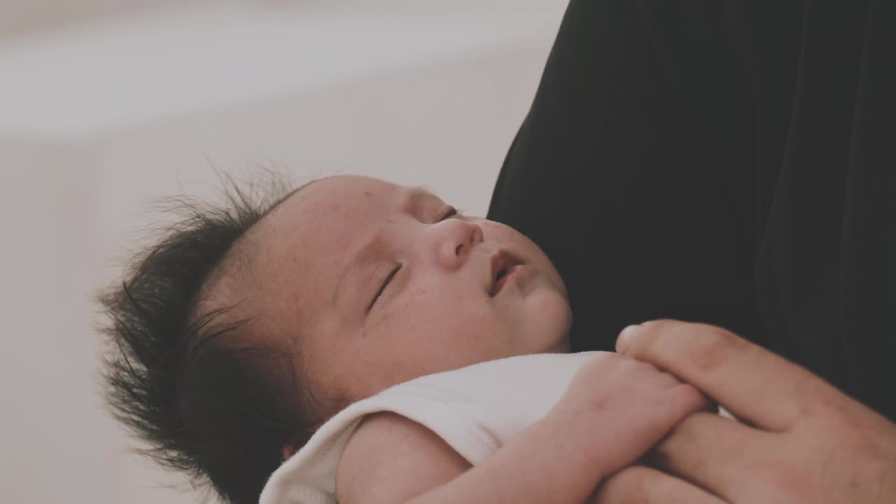 刚出生的婴儿睡在父亲的怀里。视频素材