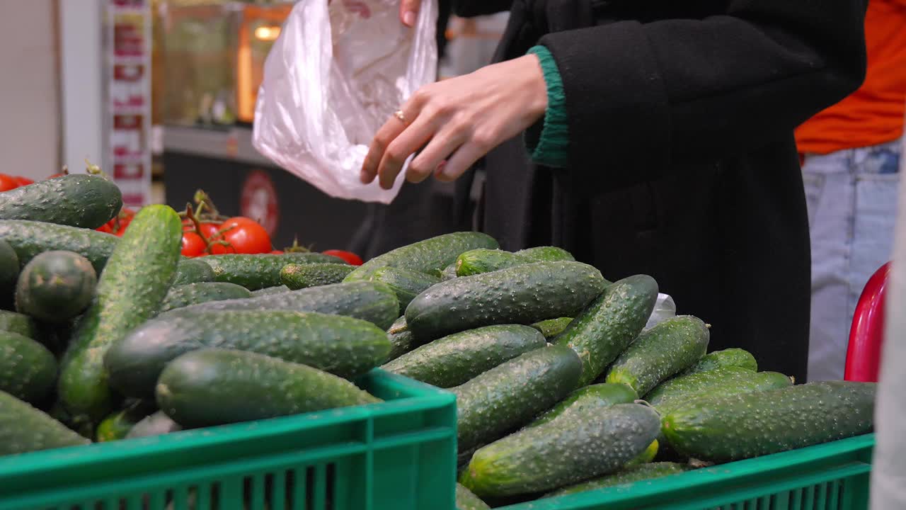 妇女在商店里把黄瓜放进袋子的特写。视频素材