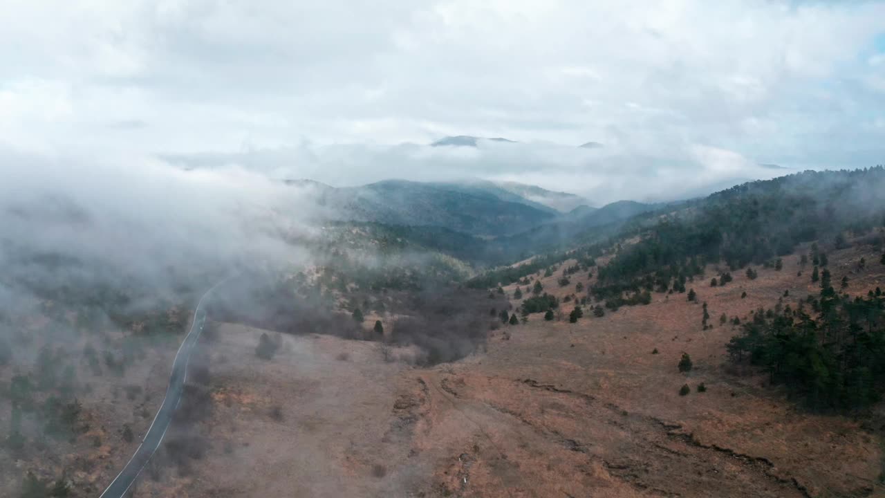 云雾缭绕的山景配上蜿蜒曲折的道路，唤起一种宁静的心情，清晨，鸟瞰视频素材