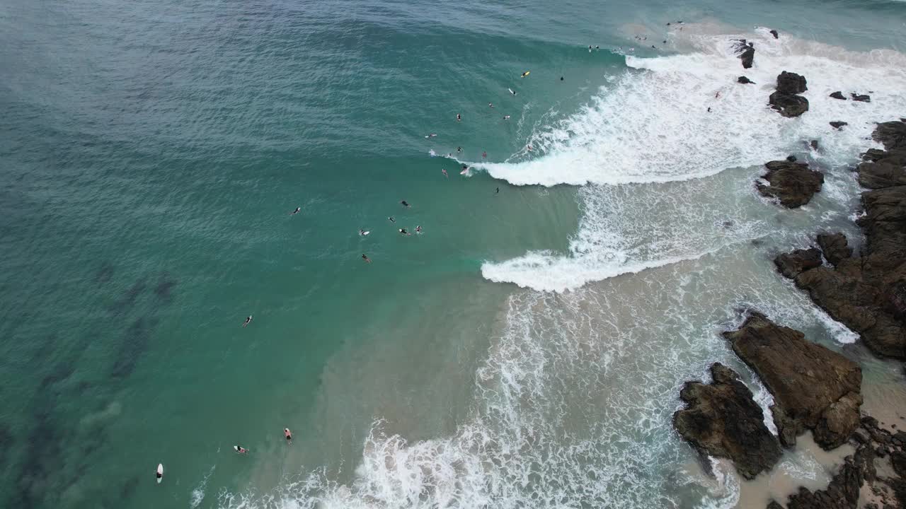 海浪和冲浪者享受在拜伦湾，新南威尔士州，澳大利亚的通行证海滩-空中无人机拍摄视频素材