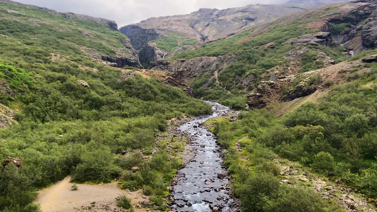 在雾蒙蒙的日子里，小山河流经冰岛的岩石山谷视频素材