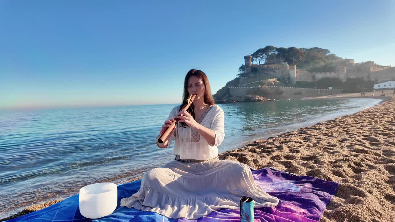 美丽的高加索女人在晴朗的日子里在空旷的海滩上吹木笛，4K视频素材