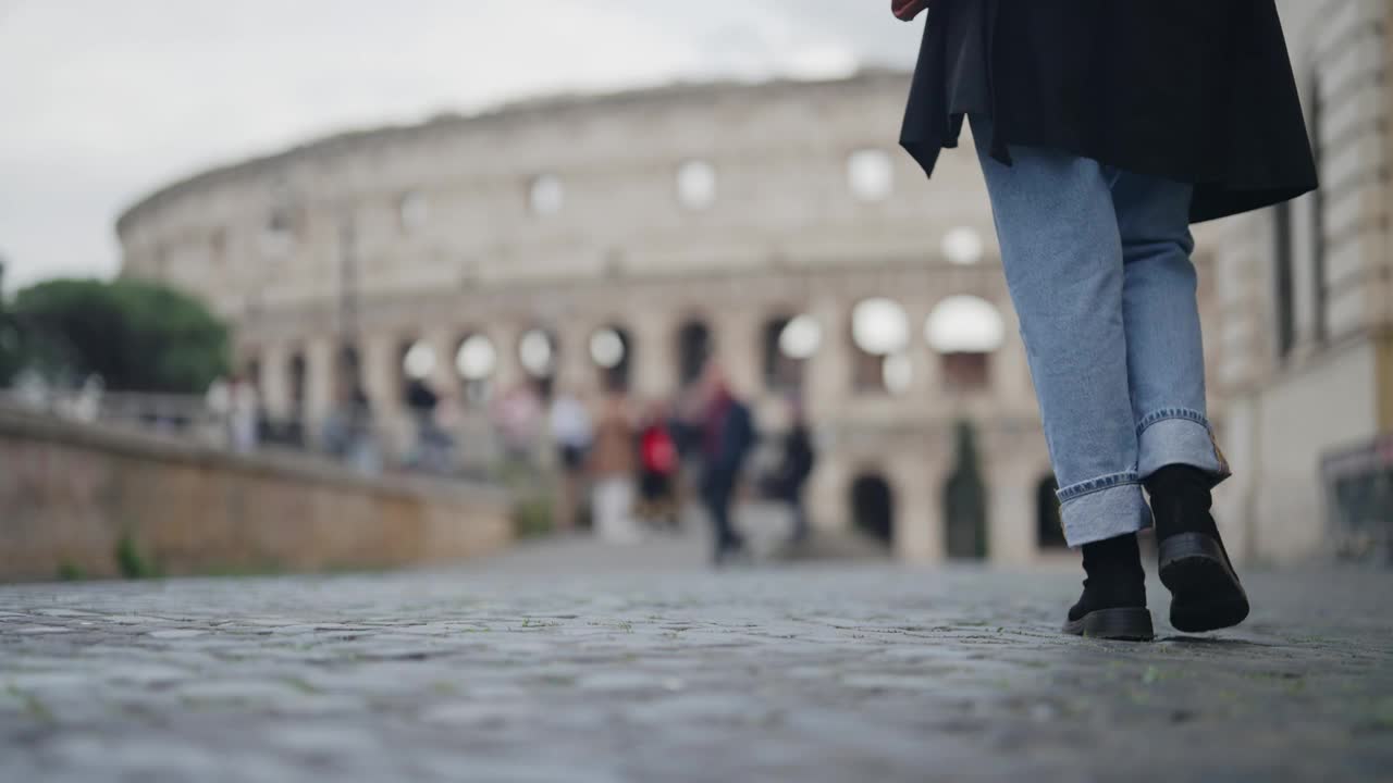 女商人走在罗马的人行道上，背景是罗马斗兽场，慢动作电影式的单独镜头，选择性聚焦视频素材