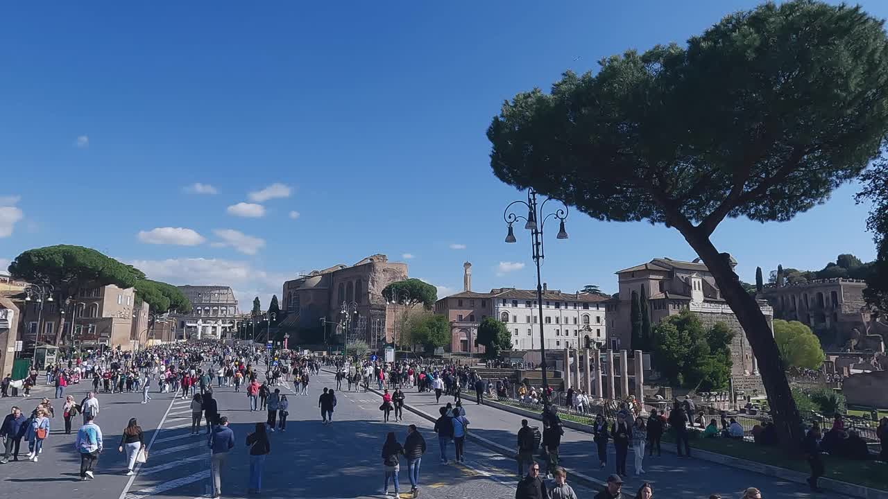 航拍的一群游客走在Via dei Fori Imperiali大道上，可以看到罗马斗兽场和罗马广场。东部节日期间，街道是人行道，慢动作视频素材