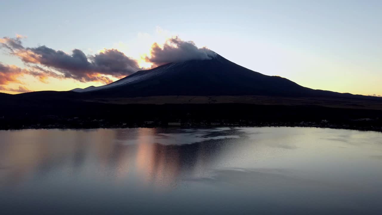 夕阳的色调反射在水面上，富士山的剪影映衬着昏暗的天空，云层聚集视频素材