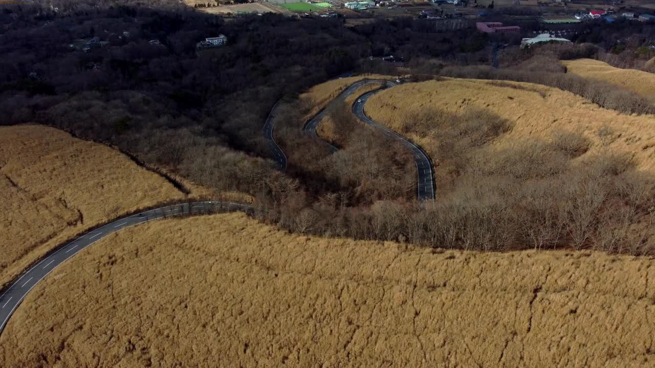 弯弯曲曲的道路蜿蜒穿过金色的山丘，鸟瞰图，傍晚的光线视频素材