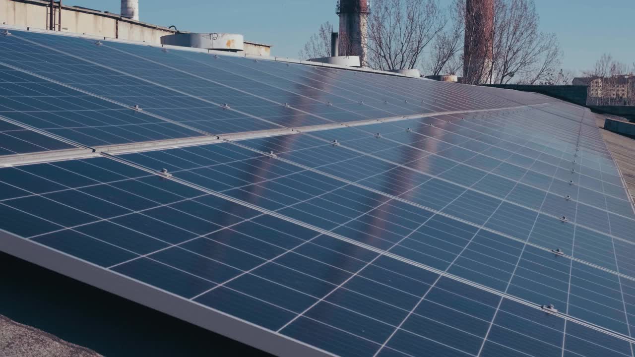 工业建筑屋顶的光伏太阳能板。太阳能电池板和蓝天。视频下载