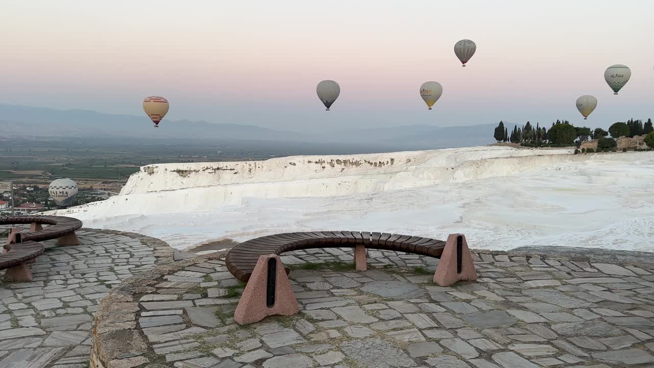 在Pamukkale，日出时热气球漂浮在露天矿物温泉上的广角镜头。视频下载