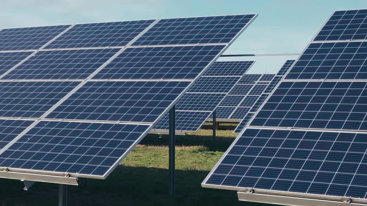 太阳能公园里的光伏太阳能电池板。绿色的草地和蓝天上的太阳能电池板。视频下载