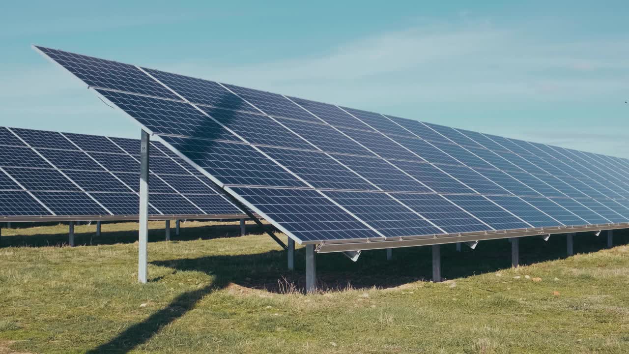 太阳能公园里的光伏太阳能电池板。绿色的草地和蓝天上的太阳能电池板。视频素材