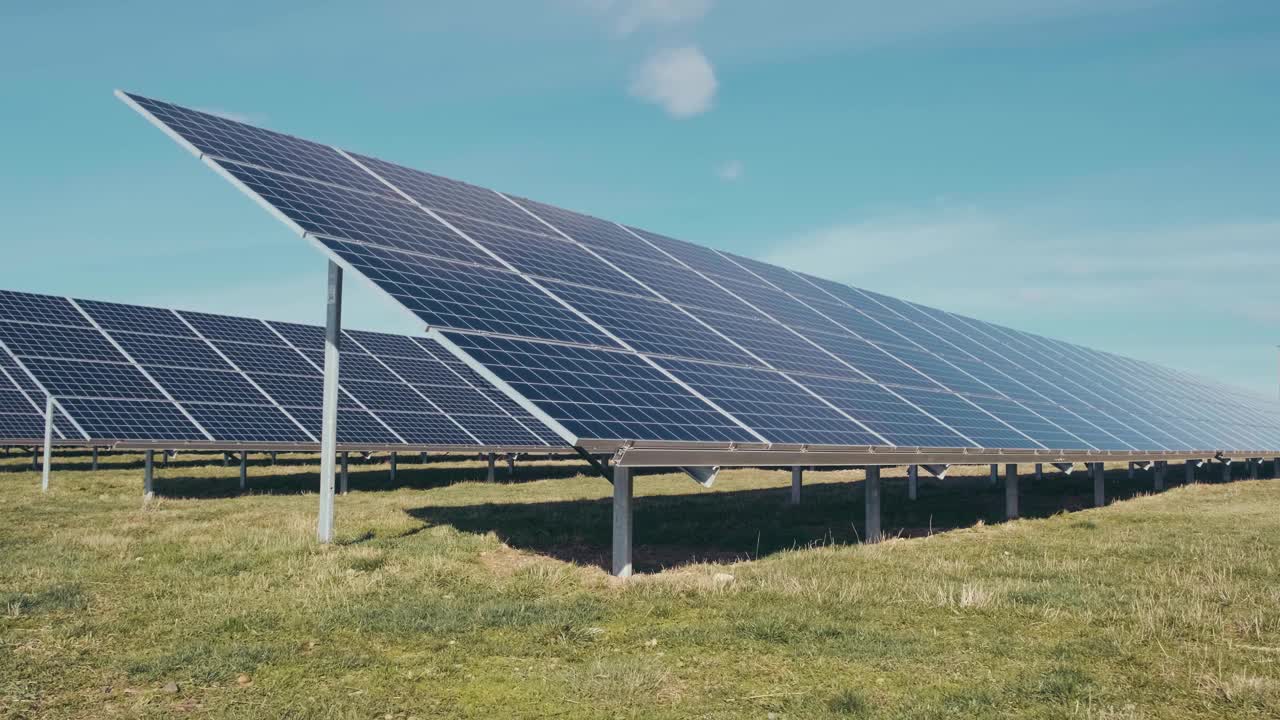 太阳能公园里的光伏太阳能电池板。绿色的草地和蓝天上的太阳能电池板。视频下载