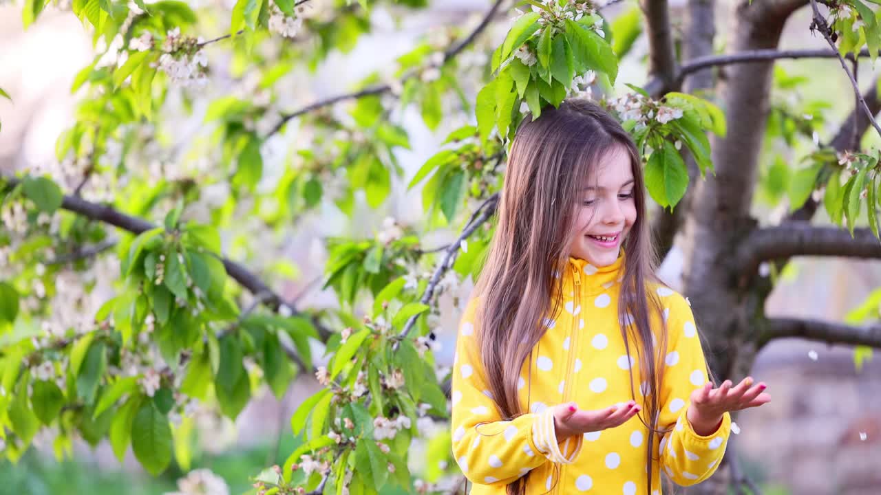 快乐可爱的小女孩享受春天的苹果树盛开的花瓣在农村的苹果花园视频视频素材