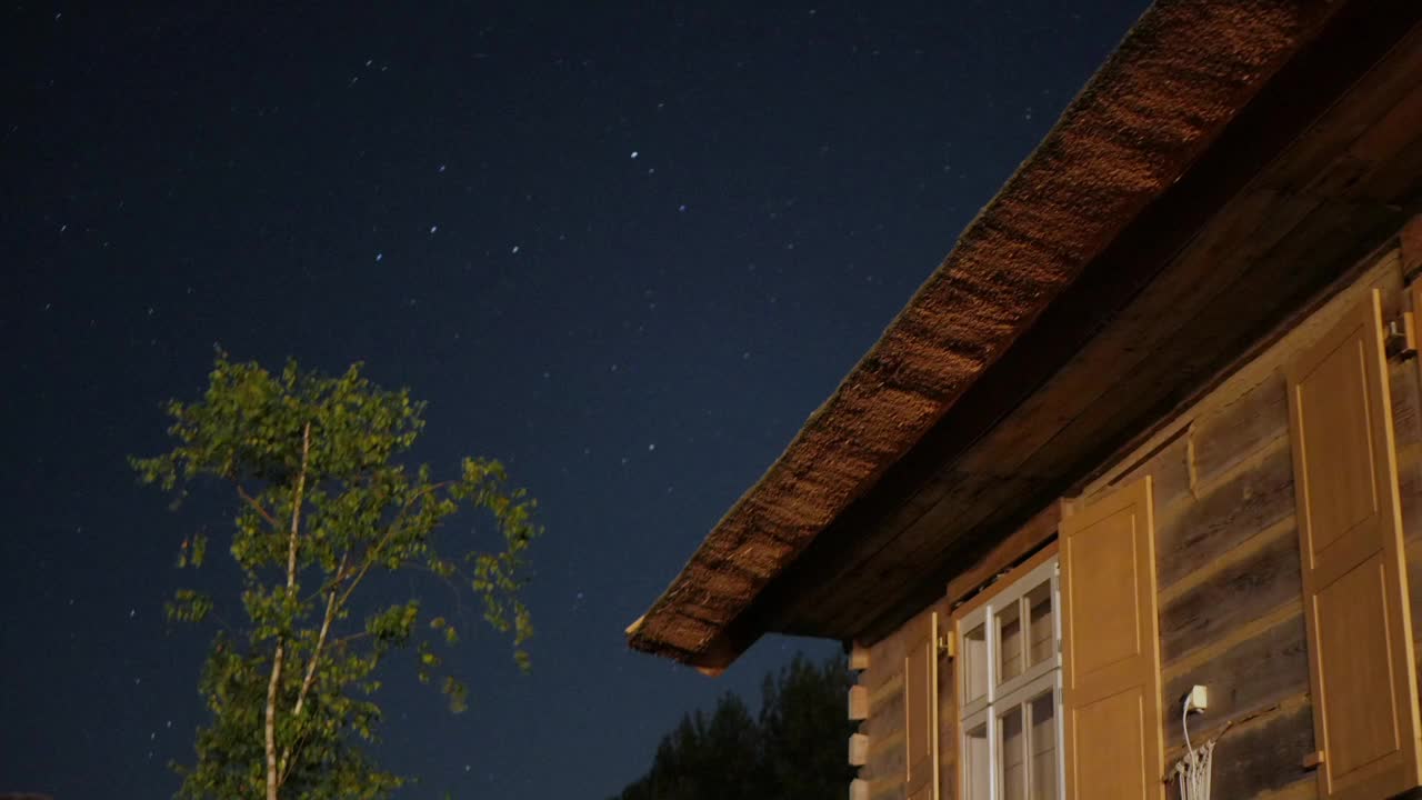 夜空与树木和茅草屋顶古老的乡村舒适的房子视频素材