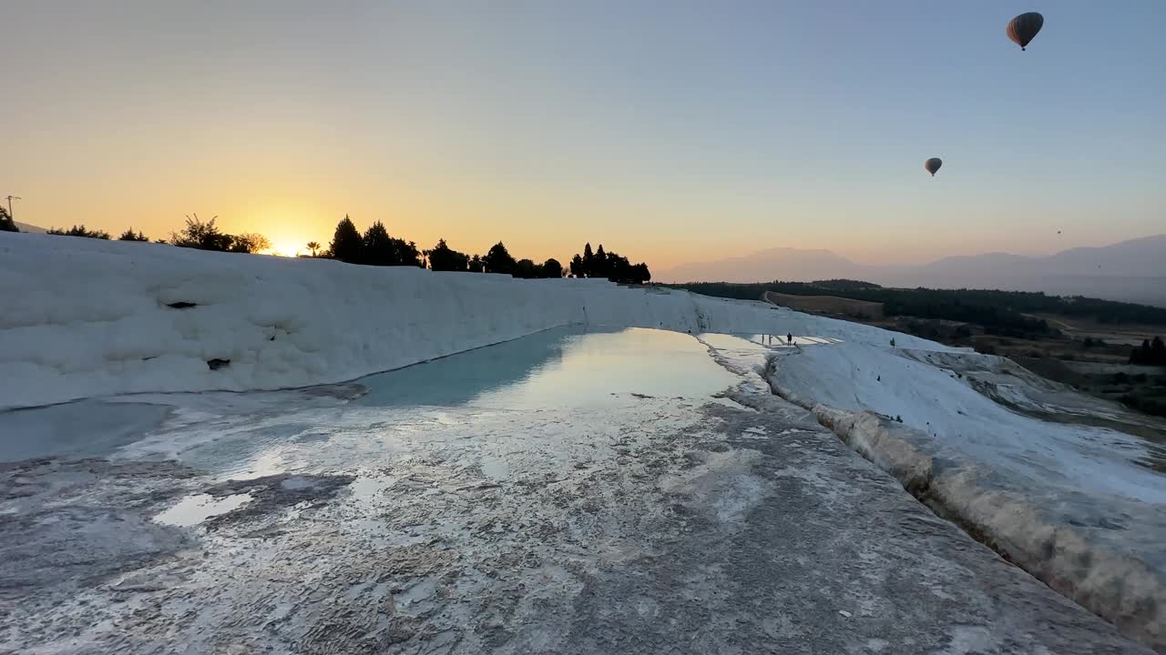 在Pamukkale，日出时热气球漂浮在梯田矿物温泉上。视频下载