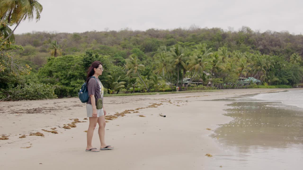 一个女人独自走在格林纳达的大安斯海滩上，平静的一天，柔和的海浪和热带的背景视频素材