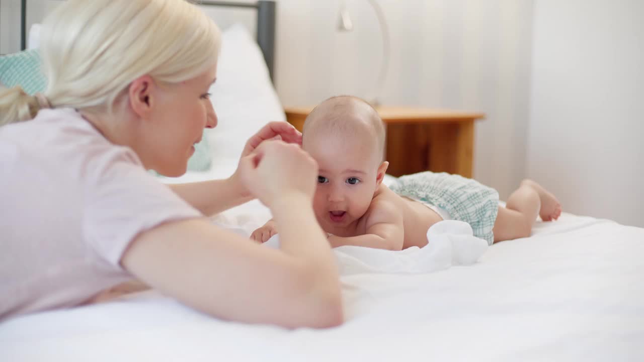 Mom and baby boy cuddling on the bed in the morning视频素材