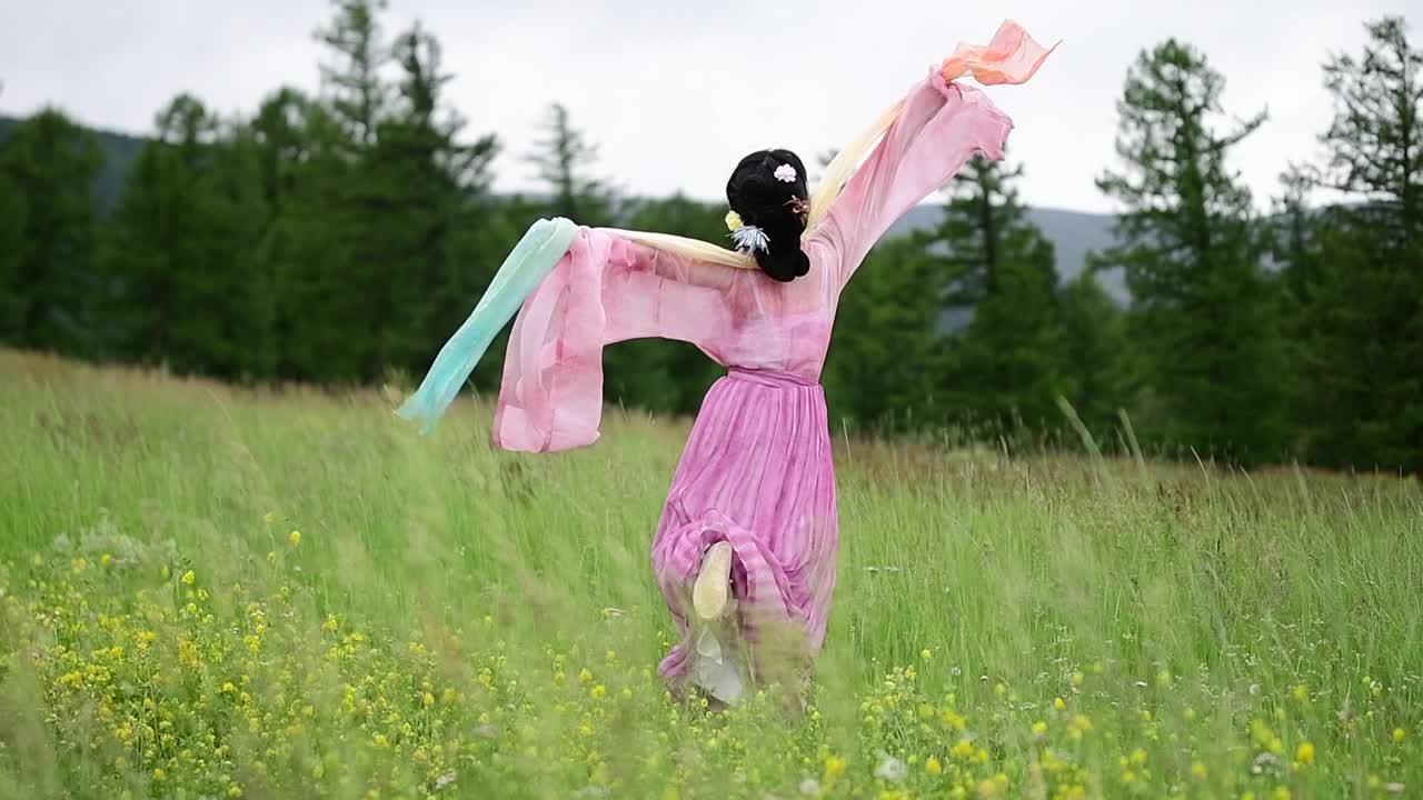 在中国新疆哈密的草原上，一个穿着中国传统服装的亚洲女孩翩翩起舞视频下载