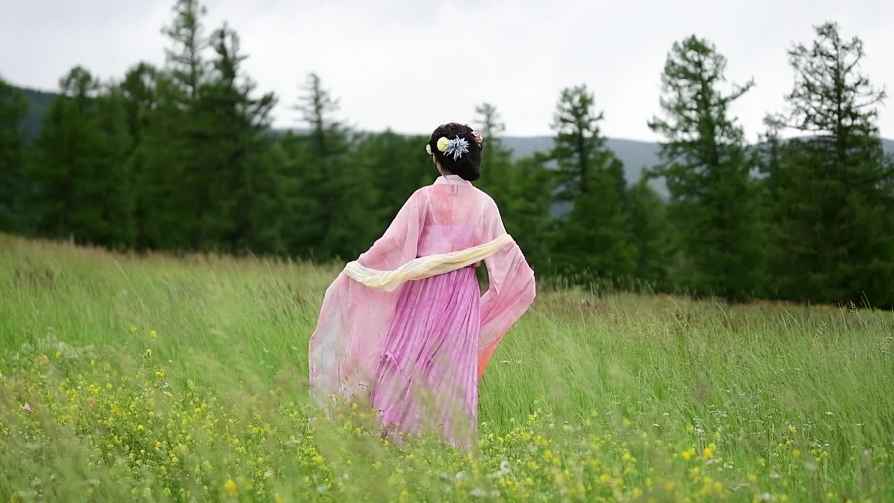 在中国新疆哈密的草原上，一个穿着中国传统服装的亚洲女孩翩翩起舞视频下载