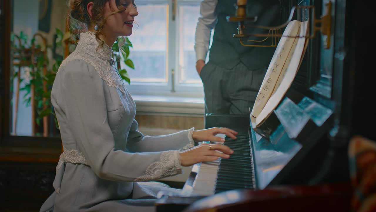 浪漫的年轻女子在19世纪的复古室内为男人弹钢琴，4K，普罗斯视频下载