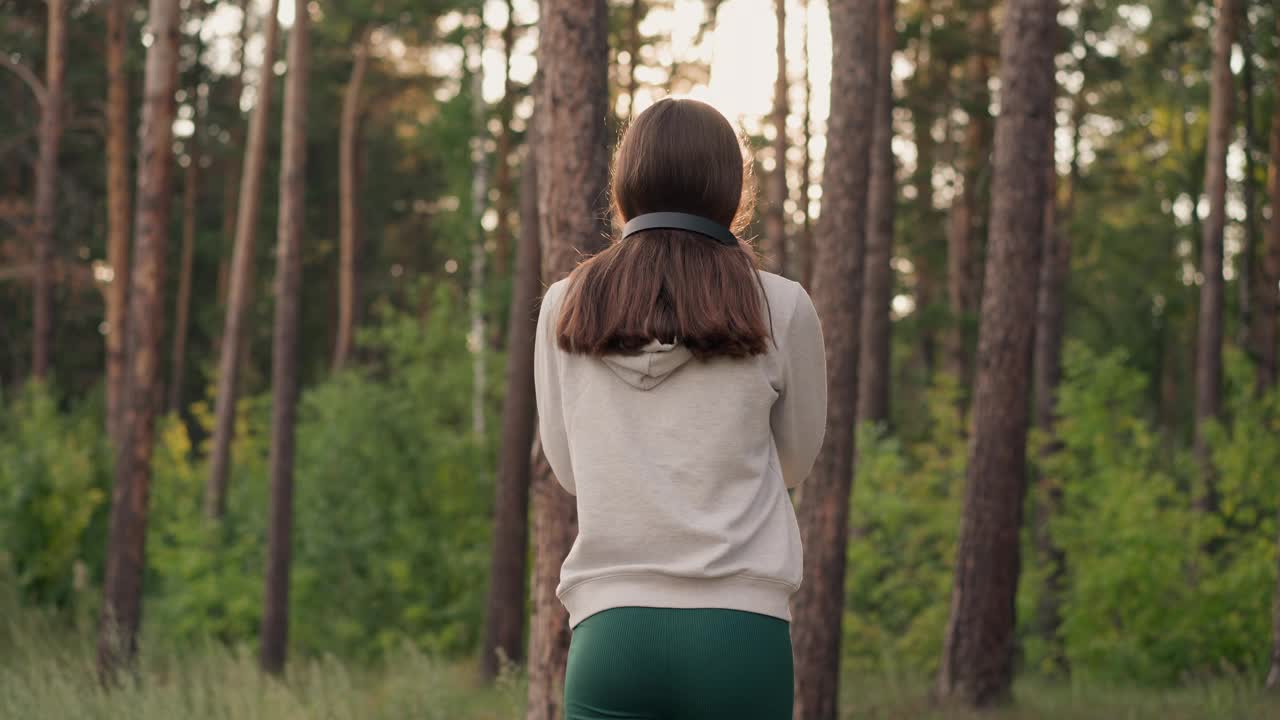 女人戴着耳机在森林里奔跑视频素材