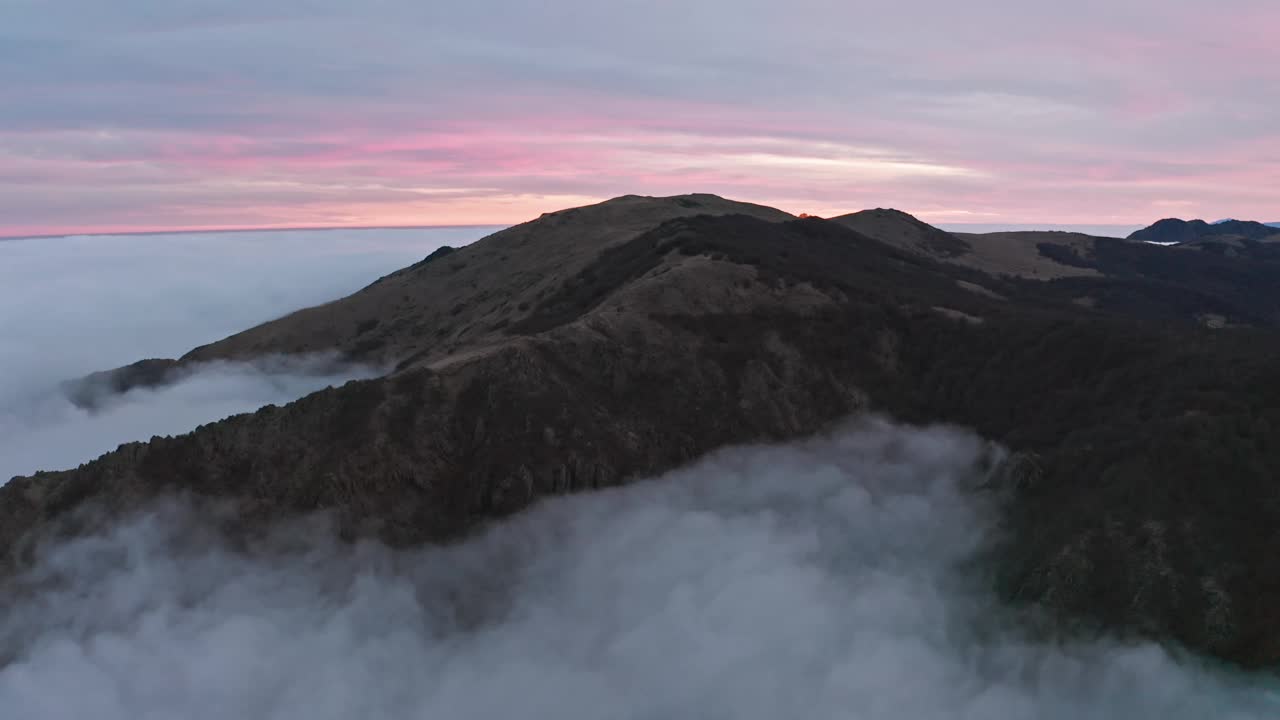 薄雾笼罩的山峰在黄昏与柔和的粉红色天空，鸟瞰图视频素材