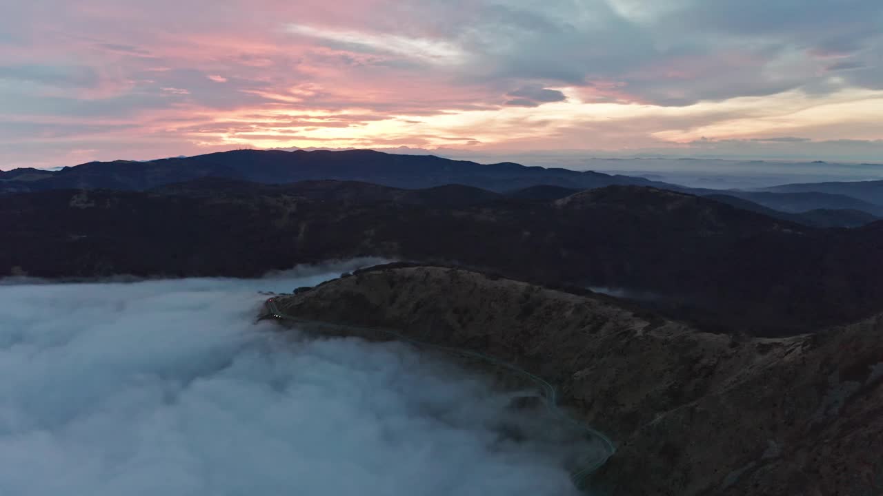 黄昏时云雾缭绕的山脉，白云笼罩山谷，鸟瞰图视频素材