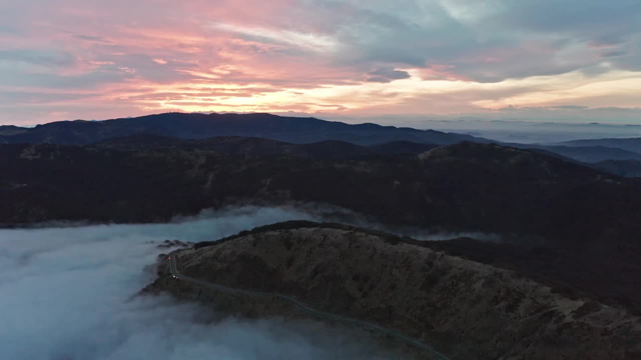 雾蒙蒙的山路在日出与软云和温柔的光，鸟瞰图视频素材