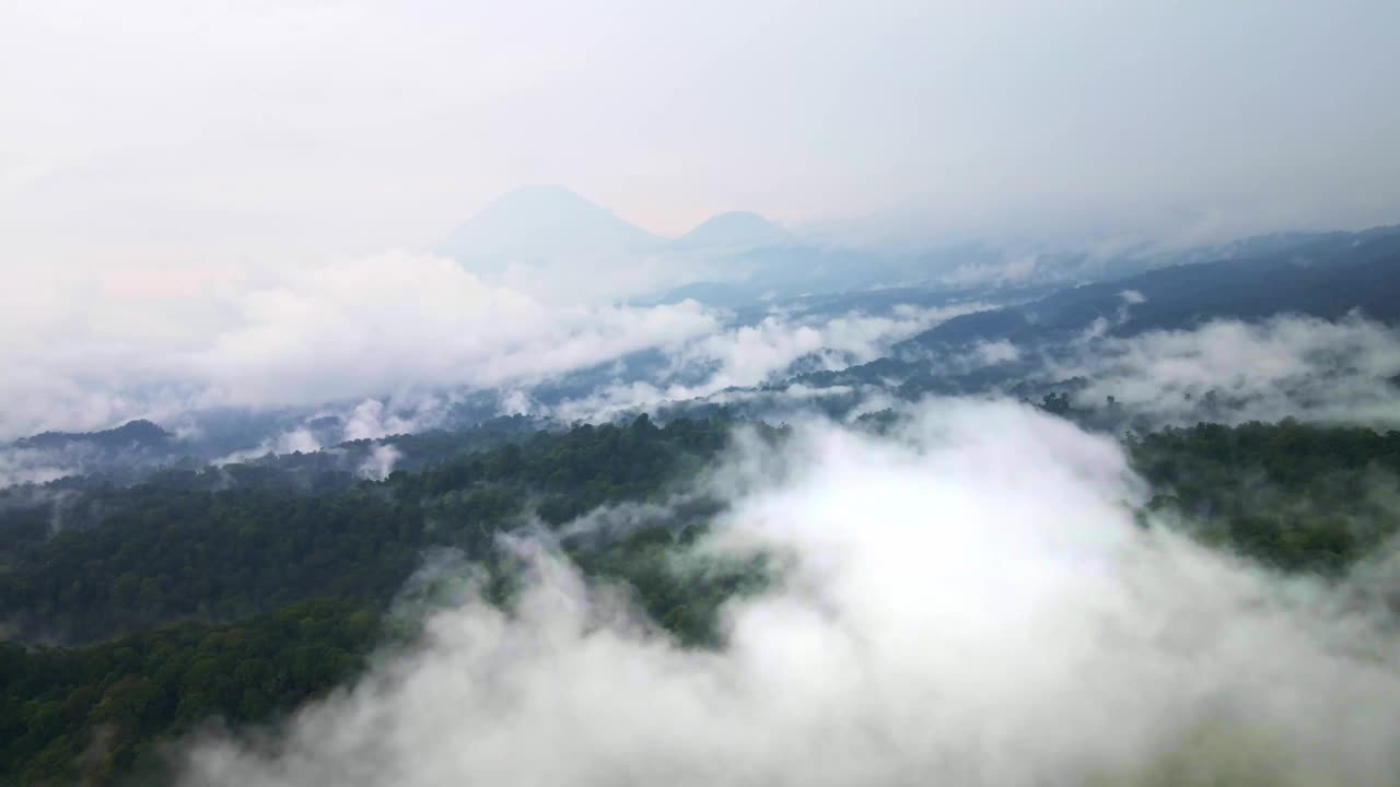 在充满活力的热带雨林上空的航拍镜头，背景是一座活火山，突出了保护工作，航拍4k无人机镜头视频素材