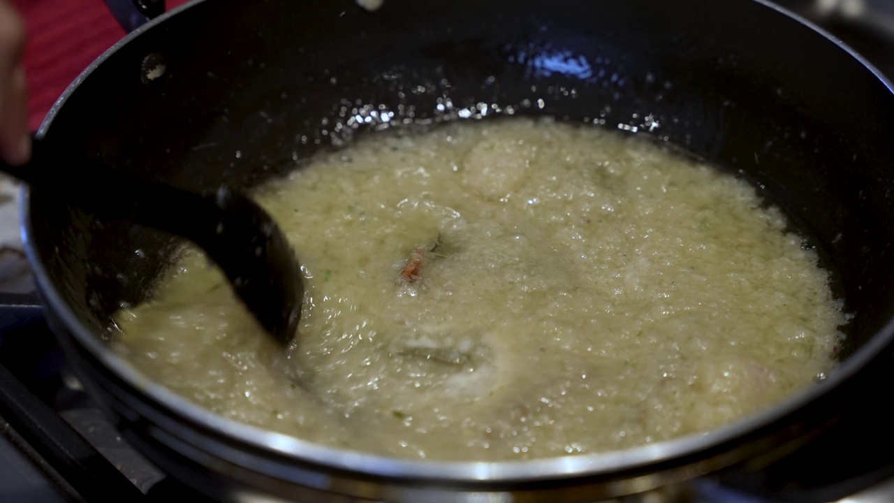 用勺子搅拌锅里的洋葱，唤起烹饪的精髓和细致的食物准备。慢动作视频素材